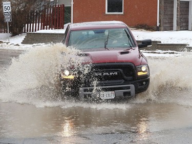 A vehicle drives through water that partially covered Sixth Avenue in Lively, Ont. on Thursday March 31, 2022. John Lappa/Sudbury Star/Postmedia Network