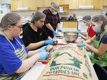 Cadence Garand, left, Matthew Haan, food and nutrition teacher Alicia Doiron, Liam Brouillette and Nova Willet peel potatoes for the 15th annual holiday feast at Sudbury Secondary School in Sudbury, Ont. on Wednesday December 14, 2022. The dinner is being held at the high school on Dec. 15. About 700 staff and students from the high school, as well as Grade 7 and 8 students from Lansdowne Public School and Princess Anne Public School will be chowing down on turkey, stuffing, cranberry sauce, potatoes, coleslaw, buns and ice cream. The feast includes 500 pounds of turkey, 300 pounds of potatoes and 150 pounds of vegetables, thanks to support from corporate sponsors. John Lappa/Sudbury Star/Postmedia Network