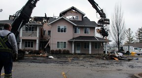 Scott Barr, hired by a property restoration company to put up fencing around Fairwinds Lodge retirement home, watches on Tuesday Jan 17, 2022 as a heavy equipment operator removes burnt sections of the home that was heavily damaged by a fire overnight Monday. (Terry Bridge/Postmedia Network)