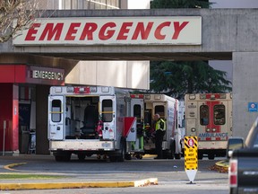 A paramedic is seen outside ambulances parked at the entrance to the emergency department at Richmond General Hospital, in Richmond, B.C., Sunday, Nov. 27, 2022. Ambulance paramedics and dispatchers in British Columbia have reached a tentative contract with the provincial government after mediated negotiations.