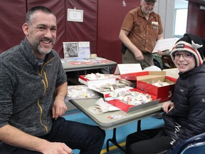 Ryan Sim and his 11-year-old son Elliot dig through shoeboxes full of free stamps offered to children at the Brantford Stamp Club's youth booth. The club held its stamp show on Saturday at the Branlyn Community Centre.