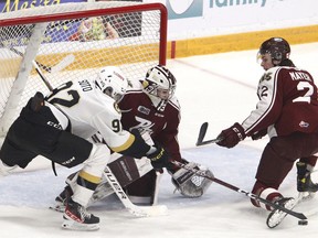Kingston Frontenacs forward Matthew Soto pokes at a rebound kicked out by Peterborough Petes goaltender Michael Simpson next to Samuel Mayer during the first period of an Ontario Hockey League game on Monday, Jan. 16, 2023, in Peterborough.