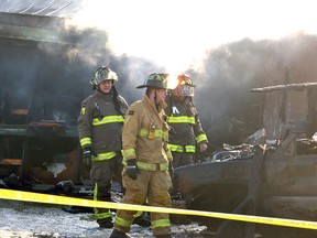 Firefighters survey the burned-out wreckage of a vehicle destroyed in an industrial fire on Monteith Avenue Monday morning. (Galen Simmons/Beacon Herald)