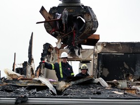 From left, John Milne, a fire prevention officer with the Sarnia department, and Mike Bird, an investigator with the Ontario Fire Marshal's office, watch on Jan.  17 as a heavy equipment operator removes burnt sections from Fairwinds Lodge retirement home, which was heavily damaged by a fire two days earlier.  (Terry Bridge/Sarnia Observer)