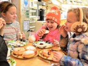 Lucy Fox, 10, digs into a paczki during a recent trip to Courtland Bakery as Stella Jagt, left, and Lucy Jagt contemplate their next bites.