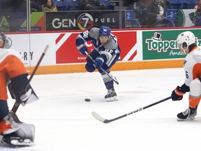 David Goyette, middle, of the Sudbury Wolves, fires the puck at Nathan Day, of the Flint Firebirds, during OHL action at the Sudbury Community Arena in Sudbury, Ont. on Friday January 13, 2023.