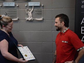 Deputy Mayor Heather Spearman presents Chad Anheliger with an award with his new plaque hanging on the wall behind them during the Elite Airdrie Athlete Award ceremony on February 9.