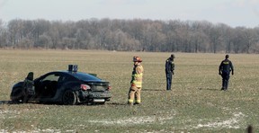 A pair of Lambton OPP officers and a Petrolia and North Enniskillen firefighter investigate after a car crashed into a field near Petrolia Saturday afternoon.  Terry Bridge/Sarnia Observer/Postmedia Network