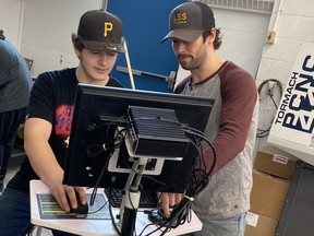 Liam Kitlar, a Grade 12 student in the millwright program at Lasalle Secondary School, left, learns how to program a component into G code with Millwright and Manufacturing teacher Alex Benoit.