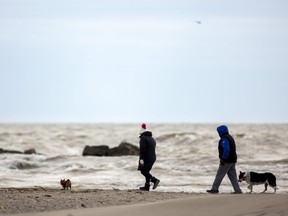 Mindy Brown and Craig Pyne of Norwich walk their pooches Romeo and Dora along the shoreline at Port Stanley on Sunday Feb. 19, 2023. Mike Hensen/The London Free Press/Postmedia Network