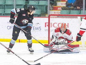 Prince George Cougars goalie making a save next to a Portland Winterhawks player