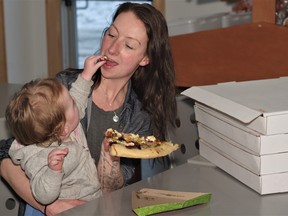 Adele O'Brien taking a bite of her pizza creation courtesy of her one-year-old daughter Norah.  O'Brien is among several Powassan residents who have been part of a weekly promotion by the Carriage House Market where they suggest what ingredients to put on pizzas.