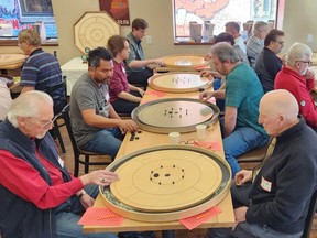 Players are shown Saturday during the February Frosty Flick, a National Crokinole Association-sanctioned tournament, at Turns & Tales: Chatham Board Game Café and Bookstore. (Trevor Terfloth/The Daily News)
