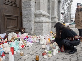 A woman lights a candle at a memorial outside a church close to the site of a daycare centre in Laval, Que, Thursday, February 9, 2023, where a bus crashed into the building killing two children. The parents of one of the two children who died have paid tribute to their four-year-old daughter in a letter sent to Quebec media.THE CANADIAN PRESS/Graham Hughes