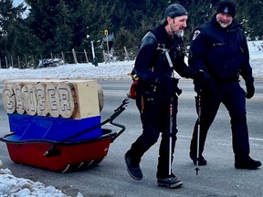 Mike Duhacek pulls his sled through Owen Sound, Ont. while escorted by a city police officer on Saturday, Feb. 4, 2023. (Supplied photo)