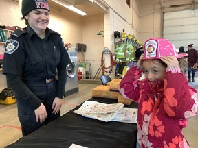 Seven-year-old Eliza Pauloff, right, tries on a plastic fire hat given by Cainsville firefighter Jessica Paczkowsk, who volunteered at a fundraiser hosted by the Paris Fire Station on Saturday, Feb.  18 in support of local restaurateur Scott Dammeier who is being treated for terminal bladder cancer.  SUSAN GAMBLE PHOTO