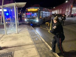 Kingston Police officers put tape around the scene where a Kingston Transit bus knocked over a traffic light pole and damaged a bus shelter in Kingston, Ont., on Tuesday, Feb. 21, 2023.