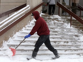 Kohl Kreimes, shovels the stairs of Queen's University Goodwin Hall on Union Street on Thursday. It was a day after a large snowstorm hit the area. Kreimes was part of a team of shovelers from Sheldon's Property Maintenance working around the Queen's University campus.