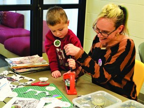 Sam Bonwick, the Pincher Creek Municipal Library's outreach coordinator, got a little help making lapel buttons from five-year-old Alexander Ingram at the Family Literacy Day event held at the library on Friday, Jan. 27. DANA ZIELKE