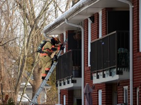 A Petrolia and North Enniskillen firefighter climbs a ladder into a unit of an apartment building on Greenfield Street where a fire broke out Sunday afternoon.  (Terry Bridge/Sarnia Observer)