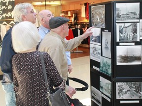 A group of Lambton Mall patrons examine the Sarnia Heritage Committee's vast collection of historical photographs during Ontario Heritage Week. (File photo)