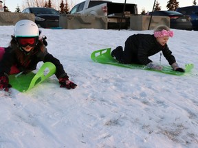 Friends (l-r) Pyper Evans, seven, and Bridgit Koopmans, seven, launched down the Dahl Drive Sledding Hill during the town’s Light Up Toboggan Party Wednesday night.