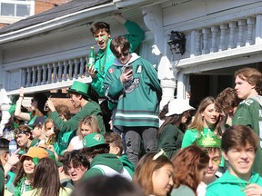 Revellers gather on a veranda during a large St. Patrick’s Day street party in the University District at the corner of University Avenue and Johnson Street in Kingston on March 17 2022.