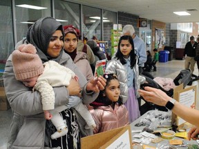 From left, Sonia Rehman, holding baby Fatima, and her other children, Rida, Wajiha and Khadija, receive a package of seeds from volunteer Julie Lanctot at the Transition into Spring showcase held at the Benson Centre on Saturday March 18, 2023 in Cornwall, Ont. Greg Peerenboom/Special to the Cornwall Standard-Freeholder/Postmedia Network