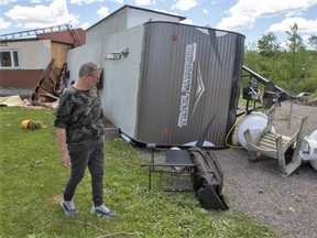Lynn Prest walks beside her damaged house and overturned trailer from the aftermath of a possible tornado in Tweed, Ont., on Monday July 25, 2022. PHOTO BY LARS HAGBERG /THE CANADIAN PRESS