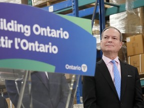 Ontario Finance Minister Peter Bethlenfalvy listens to Ontario Premier Doug Ford speak after touring the Oakville Stamping and Bending Limited facility in Oakville, Ont., on Wednesday, March 22, 2023.