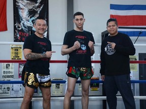 Damion Smith (centre) stands with coaches Luis Cofre (left) and Philip 'Cutman P' Garduque in the ring at the Airdrie Martial Arts Centre. Smith won a gold medal at the Muay Thai World Cup on March 25.