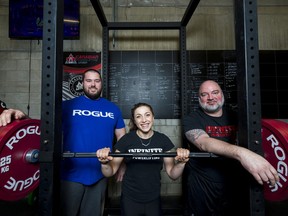 From left, Trevor Greenwood, Nicola Paviglianiti and Dale Willicombe pose alongside a squat rack inside the Infinite Martial Arts & Fitness gym in Belleville on Sunday. ALEX FILIPE