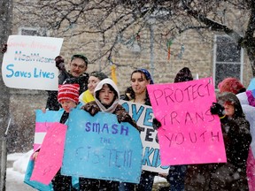 Demonstrators hold up signs calling for the protection of the rights of transgender people in front of the Brockville Public Library on Tuesday afternoon. (RONALD ZAJAC/The Recorder and Times)
