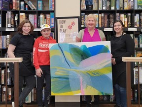 Josh White, second from left, with help from his dad, Josh, who is not pictures, found the painting Sweet Sunshine made by Chatham-Kent artist Vicki McFarland, third from left, at Turns and Tales in downtown Chatham on Sunday during international art and found day. The day saw artists across the world hide paintings in their communities and leave clues about their locations on social media. The painting was found after McFarland left the second clue. Also shown are Meghan DaSilva, left, and Shyra Thibeault, right, from Turns and Tales. (Handout/Postmedia Network)