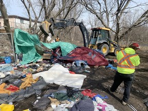 City workers clear garbage from the encampment next to the Integrated Care Hub in Kingston on Wednesday.