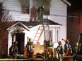 Flames flare up behind a Kingston firefighter as he prepares to climb down from the second storey of the house at 895 Montreal St. in Kingston on Thursday night.