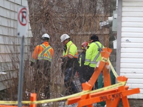 Fire officials on Friday look at the back corner of a building where a house fire Thursday night killed two people in Kingston.