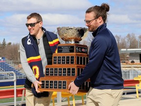 Queen's Gaels football alumni Marty Gordon, left, and Ben D'Andrea, 2009 Vanier Cup champions, carry the Vanier Cup to a news conference on Thursday,, March 30, 2023, announcing that Queen's University will be hosting the Vanier Cup national university football championship at Richardson Stadium in 2023 and 2024.