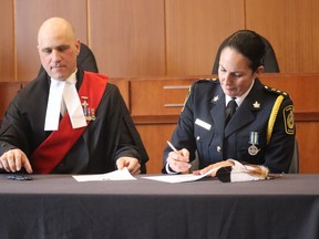 An eagle feather sits on the table next to Julie Craddock as Justice Mark Poland swears her in Monday as Sarnia police's first female and first Indigenous deputy chief of the Sarnia Police Service by Justice Mark Poland.