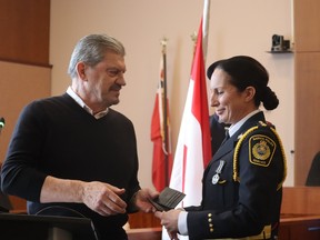 Julie Craddock, Sarnia's new deputy police chief, is handed her badge Monday by her father, Frank Craddock, a retired Toronto police staff sergeant, during her swearing-in at Sarnia city hall Monday.