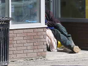 A person rests in an entrance to a vacant commercial space in downtown Sudbury, Ont. on Thursday March 30, 2023.