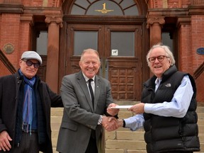 Stratford Chefs School board member in charge of marketing and recruitment David Stones (left) and board chair and president Nigel Howard (right) hand over the chefs school's final payment to Stratford Mayor Martin Ritsma on a $500,000 loan from the city that helped the school build its downtown kitchen and dining-room space five-and-a-half years ago. (Galen Simmons/The Beacon Herald)