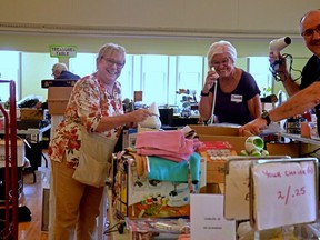 Dozens of volunteers have been working away at St. James Anglican Church in Stratford this week preparing all of the donations of household items, electronics, jewelry, treasures, books, linens, children's items and so much more for the return of the St. James Anglican Church Women's annual Variety sale after a three-year pause during the pandemic.  Pictured, president of St. James Anglican Church Women Karen Haslam and long-time variety sale volunteers Charlotte McTavish and Wade Phibbs goof around a bit while organizing some household items for the sale, which begins Thursday at 7 pm (Galen Simmons/The Beacon Herald )
