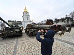 A man takes pictures of destroyed Russian military vehicles shown in an open-air exhibition in the centre of Kyiv on Feb. 24, 2023, on the first anniversary of the Russian invasion of Ukraine.