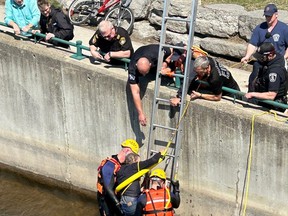 Emergency personnel assist a cyclist who wound up in the Moira River after an accident on his bike along the Riverfront Trail. BELLEVILLE POLICE