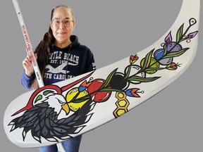 Anishinaabe artist Cathie Jamieson holds one of the 25 hockey sticks she painted to be given to the player of the game during the IIHF Women's World Championships in Brampton, Ontario.  The hockey tournament concludes on Sunday, April 16, 2023. SUBMITTED PHOTO
