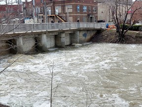 People stop by the watch the 6th Street Dam that was operating Tuesday to pump water back into the Thames River to help prevent flooding in south Chatham. PHOTO Ellwood Shreve/Postmedia