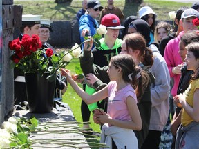 St. Lawrence Intermediate School students placing roses at the base of the Injured Workers Monument in Lamoureux Park during the National Day of Mourning event. Photo on Friday, April 28, 2023, in Cornwall, Ont. Todd Hambleton/Cornwall Standard-Freeholder/Postmedia Network