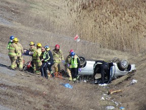 Kingston Fire and Rescue firefighters and Frontenac Paramedics carry a patient away from a vehicle that rolled into the ditch alongside Highway 401 just east of Sydenham Road in Kingston, Ont., on Monday, April 10, 2023.