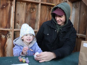 Joey DeRush holds an egg while his daughter Oakley, 2, paints during Saturday's Easter in the Park Saturday at Canatara Park.